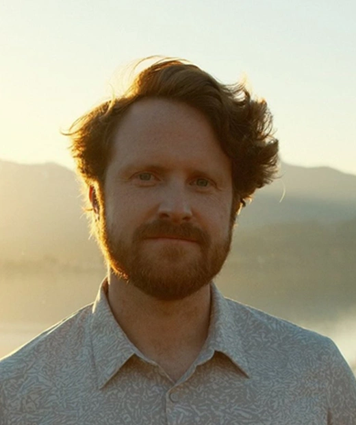 Dr. Tyler Brookings looking ahead with mountain background and sunlight on his face.