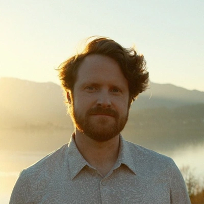 Dr. Tyler Brookings portrait, upper body, looking ahead with mountain background at sunset
