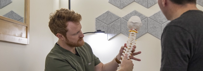 Dr. Tyler Brookings DC CCSP showing fake backbone to a patient explaining his condition